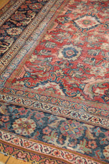 Cherry red and navy palmette patterns on vintage Persian Mahal carpet's worn pile.