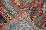 Folded corner of vintage Mahal carpet, showing detailed cherry red, navy Herati patterns, and tightly bound edge.