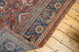 Vintage Mahal carpet corner with navy blue border, cherry red field, and tattered ends.