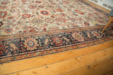 Ivory field antique Sultanabad carpet, navy blue border, blush, red, and green floral motifs.