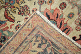 Antique Sultanabad carpet corner displaying worn floral pile, hand-knotted foundation, and short ivory fringe.