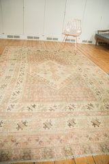 Vintage Oushak rug border showing softened ivory, blush, and brown geometric patterns with fringe.