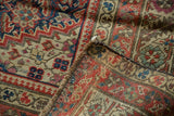 Folded corner of an antique Karabagh rug, revealing worn Herati pattern, secured edge, and hand-knotted foundation.
