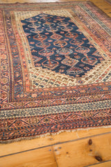 Navy, blush, and ivory geometric border patterns with fringe on the vintage Kurdish rug.