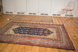 Vintage Kurdish rug corner with geometric borders in navy, chestnut brown, and ivory.