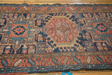Visible wear on geometric navy, red, teal patterns of a vintage Karaja rug.