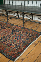Hand knotted vintage Karaja rug corner, geometric navy, madder red, and ivory designs, with fringe.