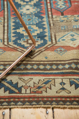 Hand-knotted geometric patterns in beige, navy, and cherry red with fringed edge.