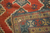 Antique Kazak runner detail showing worn madder red pile with geometric patterns and dense hand-knotted backing.