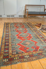 Antique Kazak runner with geometric borders, serrated red motifs, and foundation wear.