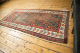 Antique Karabagh rug corner reveals red, blue geometric borders, polychrome selvage, and a storied worn field.