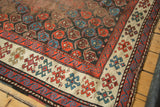 Antique Karabagh runner corner with geometric red, blue boteh motifs, ivory border, and polychrome selvage.