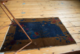 Corner view of the antique Fette Li rug's art deco brown border with raspberry florals.