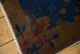 Close-up of Antique Fette Li rug corner: Art Deco florals, navy, bronze, raspberry, fringe.