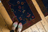 Blush, wine, green art deco florals on navy field of antique Fette Li rug.