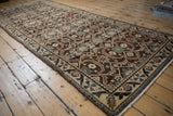 Vintage Hamadan runner corner showing geometric patterns in chocolate brown, beige, and blue with fringe.