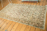 Corner of a mid-century Persian Kerman rug with ivory, blue, and dusty red floral motifs.