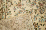 Folded vintage Persian Kerman rug revealing intricate ivory floral pile and hand knotted back.