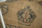 Intricate navy blue and rust paisley motif on the antique Doroksh rug's textured camel field.