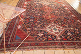 Dense pictorial motifs and geometric border on an antique Qashqai rug with wine red and navy.