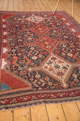 Intricate weaving showcasing birds, animals, and botanicals on the navy field of this antique Qashqai carpet.