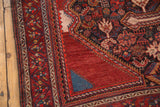 Antique Qashqai carpet corner, displaying wine red field, intricate borders, and tribal motifs.