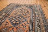 Vintage Kamseh rug displaying bright apricot, navy blue geometric medallions, and rams horn motifs.