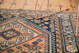 Bright apricot, navy blue, and ivory geometric patterns with rams horn motifs on the Kamseh rug.