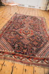 Antique Qashqai rug corner, storied fringe, red, navy geometric checkerboard border.
