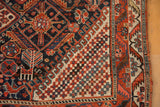 Checkerboard and geometric patterns on antique Qashqai rug in madder red, ivory, navy.
