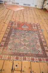 Antique Caucasian prayer rug's madder red border, blue lattice, and germinating plant motifs.