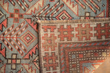Antique Caucasian rug's hand-knotted pile, showing sky blue, brick red serrated geometric motifs and fringe.