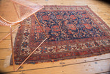 Antique Afshar rug, its navy and cherry red field displaying storied wear and tattered ends.