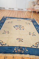 Art deco Peking carpet corner: indigo blue border, delicate floral vinery, beige field, and fringe.