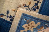 Antique Chinese Peking carpet edge, revealing beige fringe and a cobalt blue floral border.