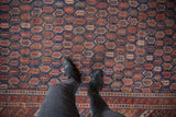 Antique Afshar carpet's rich navy and red repeating boteh pattern underfoot.