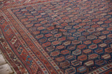 Intricate geometric border frames a navy field with repeating red boteh on an antique Afshar carpet.