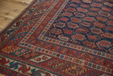 Corner of antique Afshar carpet, geometric borders in navy, cherry red, sky blue, and ivory.