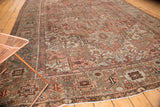 Distressed Karaja carpet corner with muted rectilinear patterns in bronze, slate blue, and ivory fringe.