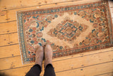 Distressed vintage Kazvin rug detail: central medallion, floral bouquets, vinery, beige, blue, apricot.