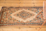 Close-up of distressed Kazvin runner's floral bouquets and scrolling vinery in apricot, beige, and sky blue.