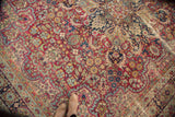 Antique Kerman carpet's mil fleur field, intricate cloud band, and natural foundation wear.