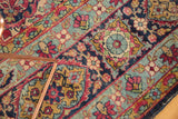 Antique Kerman carpet's mil fleur pattern in cherry red, navy, gold, showing wear.