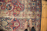 Antique Kerman carpet: mil fleur field with cherry red, navy, dusty gold, and exposed foundation.