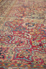 Antique Kerman carpet's mil fleur field in cherry red, featuring navy blue and ivory floral motifs.