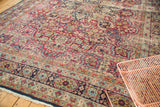 Antique Kerman carpet with intricate mil fleur field, navy blue border, and rich red tones.