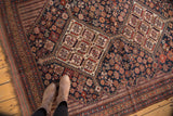 Antique Kamseh rug corner displaying intricate tribal motifs in navy, brick red, and beige.