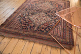 Corner of an Antique Kamseh rug, displaying low pile, geometric border, and time-softened hues.