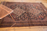 Hand knotted antique Kamseh rug corner with navy field and brick red geometric border.
