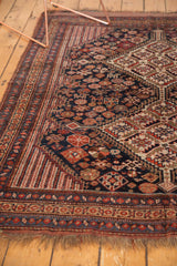 Lightly tattered fringe and navy, brick red border on antique Kamseh rug.